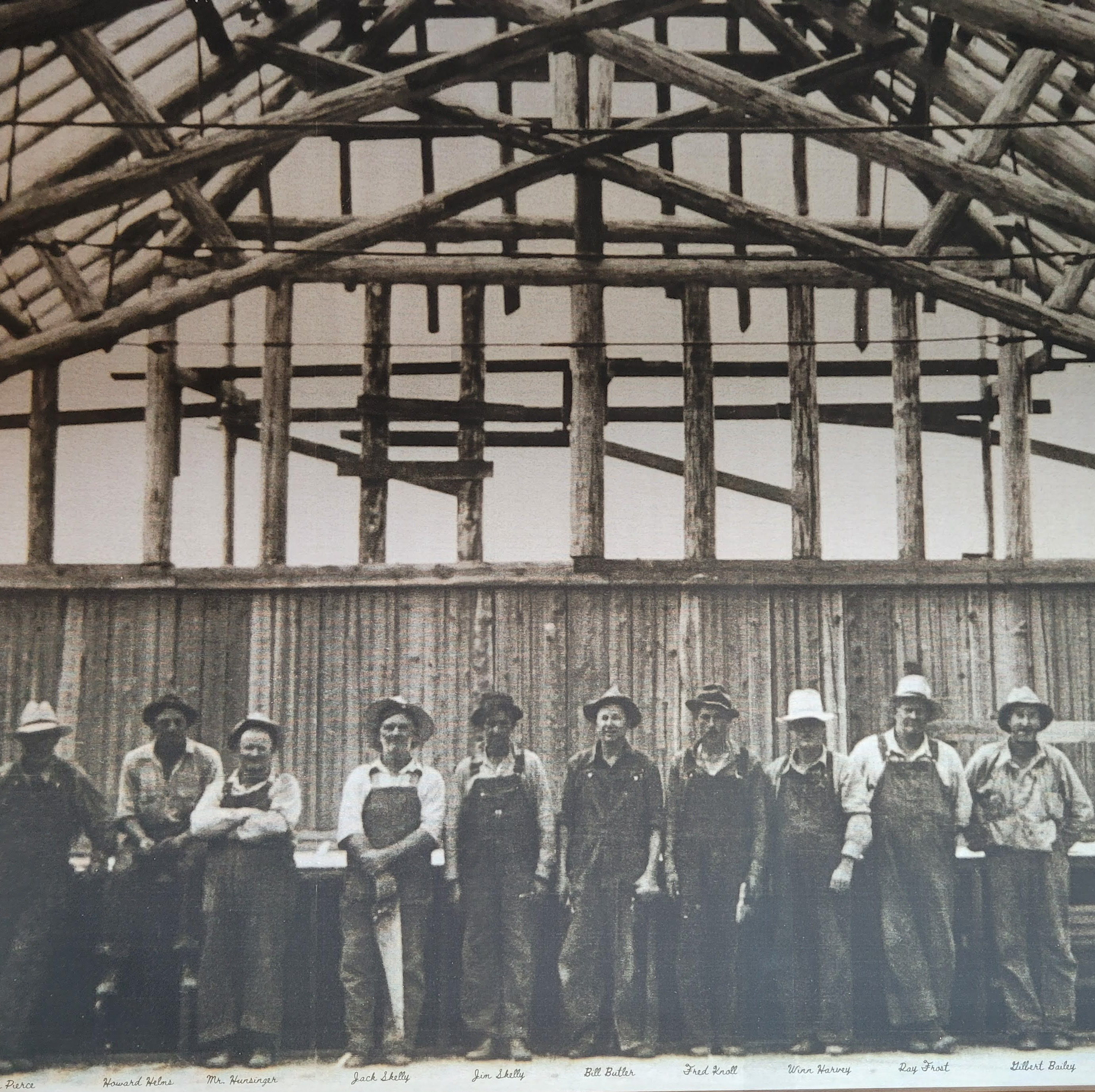 men standing inside unfinished log structure with tools